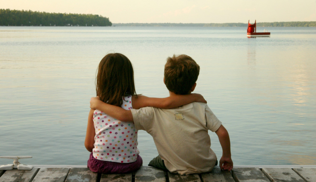 Boy and Girl Sitting by Lake