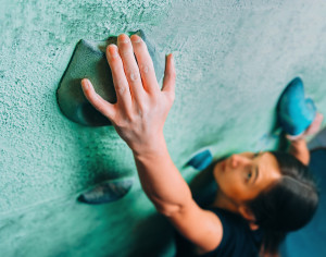 Woman Climbing Up On Wall In Gym